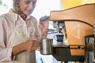 Senior waitress using coffeemaker