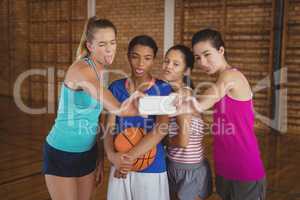 High school girls making funny faces while taking a selfie in basketball court