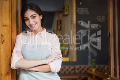 Portrait of smiling waitress standing with arms crossed