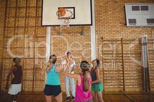 Coach helping high school team to score a goal while playing basketball