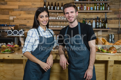 Portrait of smiling waiter and waitresses standing at counter