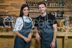 Portrait of smiling waiter and waitresses standing at counter