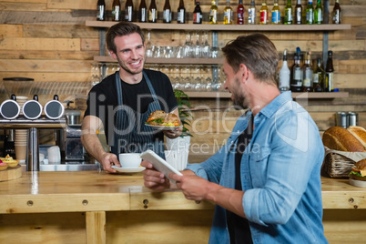 Waiter serving coffee to male customer at counter