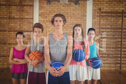 Confident high school kids holding basketball in the court