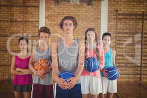 Confident high school kids holding basketball in the court