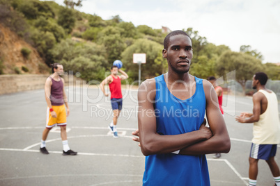 Male basketball player standing with his crossed in the court