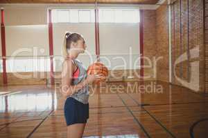 High school girl standing with basketball in the court