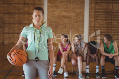 Female coach standing with basketball in basketball court