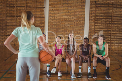 Female coach standing with basketball in basketball court