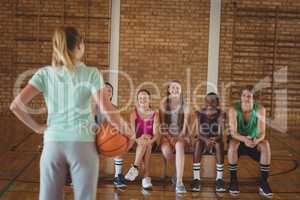 Female coach standing with basketball in basketball court
