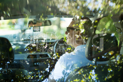Senior man driving car seen through rear windshield