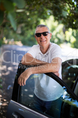 Smiling man leaning on car door