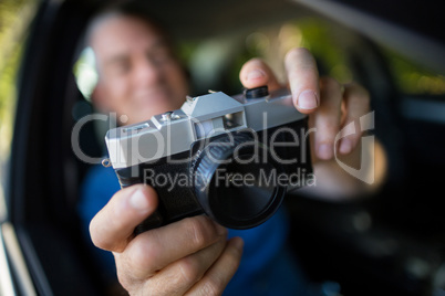 Man photographing with camera in car