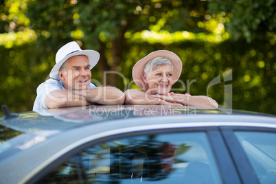 Senior couple leaning on car roof