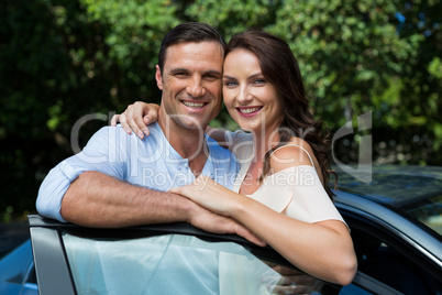 Happy couple leaning on car door