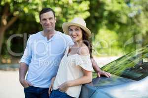 Happy young couple leaning on car