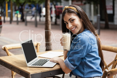 Portrait of woman using laptop while sitting at cafe