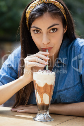 Portrait of beautiful woman drinking cold coffee at table