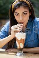 Portrait of beautiful woman drinking cold coffee at table