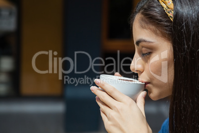 Beautiful woman drinking coffee while sitting at cafe