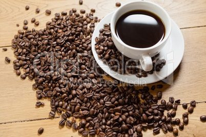 Coffee beans with cup and saucer on table
