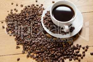 Coffee beans with cup and saucer on table