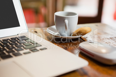 Close up of coffee cup by laptop on table
