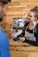 Smiling woman holding credit card reader machine