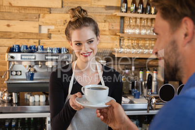 Smiling owner giving coffee to customer