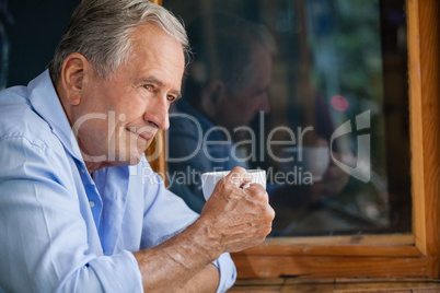Man holding coffee cup while sitting in cafe shop
