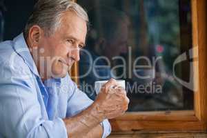 Man holding coffee cup while sitting in cafe shop