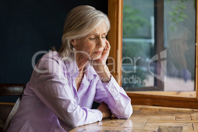 Sad senior woman sitting at table