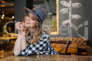 Portrait of woman leaning at table in cafe