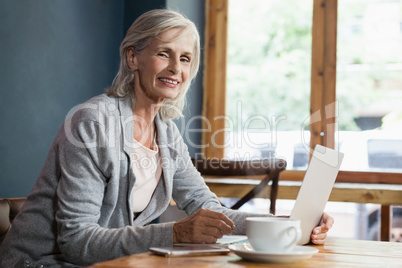 Portrait of smiling woman using laptop computer while sitting at table