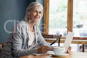 Portrait of smiling woman using laptop computer while sitting at table