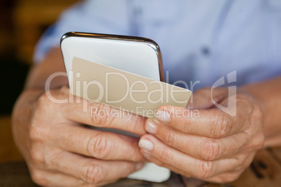 Cropped image of person holding smart phone and credit card