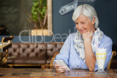 Senior woman using mobiole phone while sitting at table