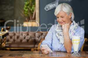 Senior woman using mobiole phone while sitting at table