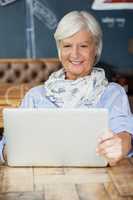 Smiling senior woman using laptop while sitting at table
