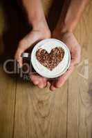 Cropped image of person holding coffe cup with frothy art