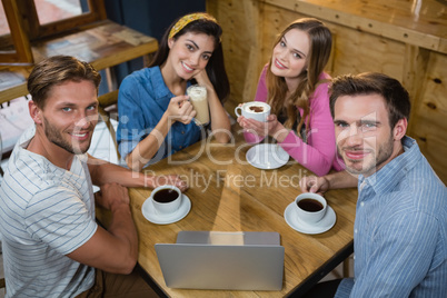 Portrait of happy friends having coffee at table