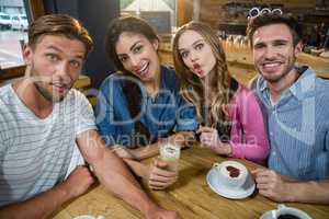 Portrait of happy friends making faces while having coffee