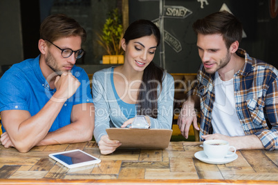 Friends discussing over clipboard while having coffee