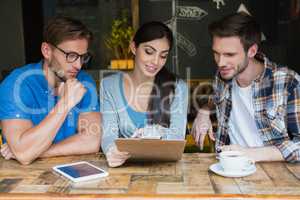 Friends discussing over clipboard while having coffee