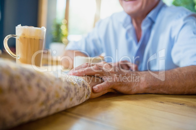 Senior couple holding hands while having coffee