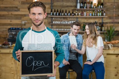 Waiter holding chalkboard with open sign and customer in background