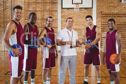 Smiling coach and basketball player standing in the court