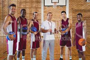 Smiling coach and basketball player standing in the court