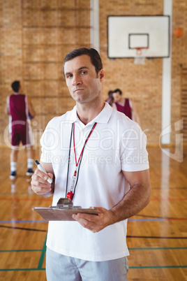 Basketball coach holding clipboard in the court