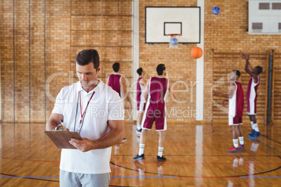 Basketball coach writing on clipboard